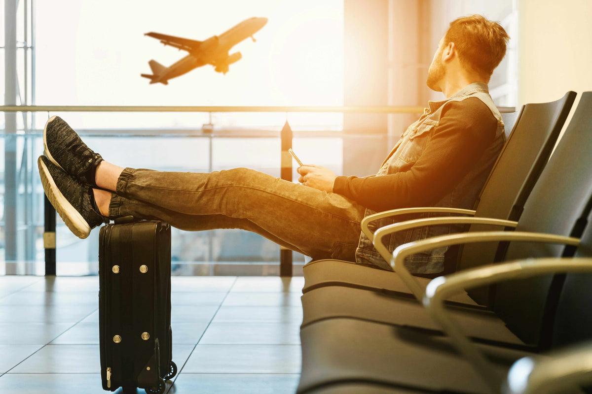 Traveller waiting at an airport with a plane taking off outside the window